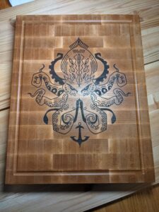 End-grain maple cutting board with a Kraken design inlaid in walnut.