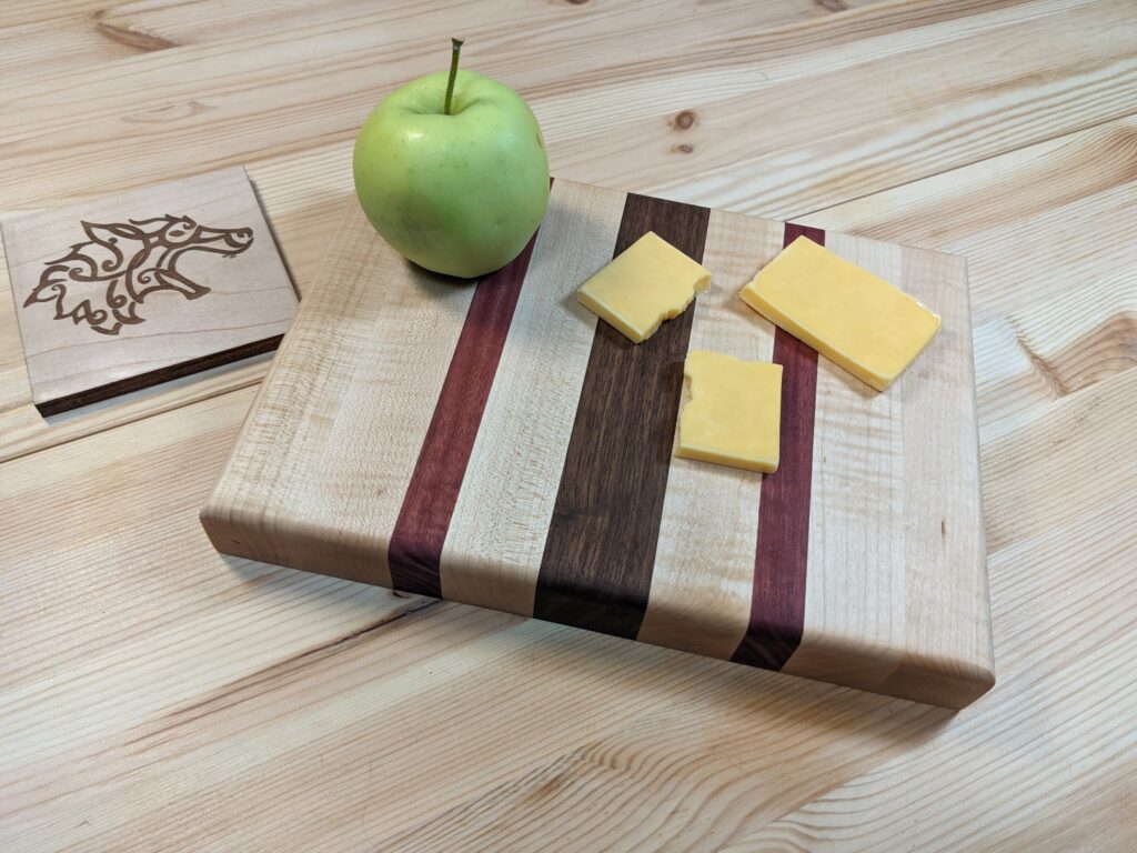 Maple cheese board with walnut and purple heart stripes and an apple and cheese slices on top