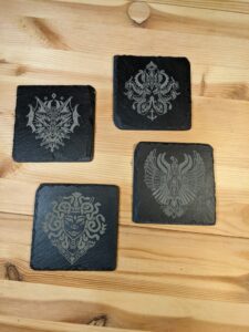 4 slate coasters with stylized Medusa, Kraken, Phoenix, & Sea Dragon